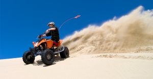 A person riding an ATV on a sand dune