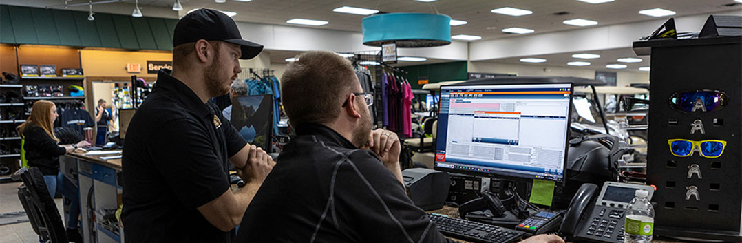 Two men behind a service desk looking at a computer monitor