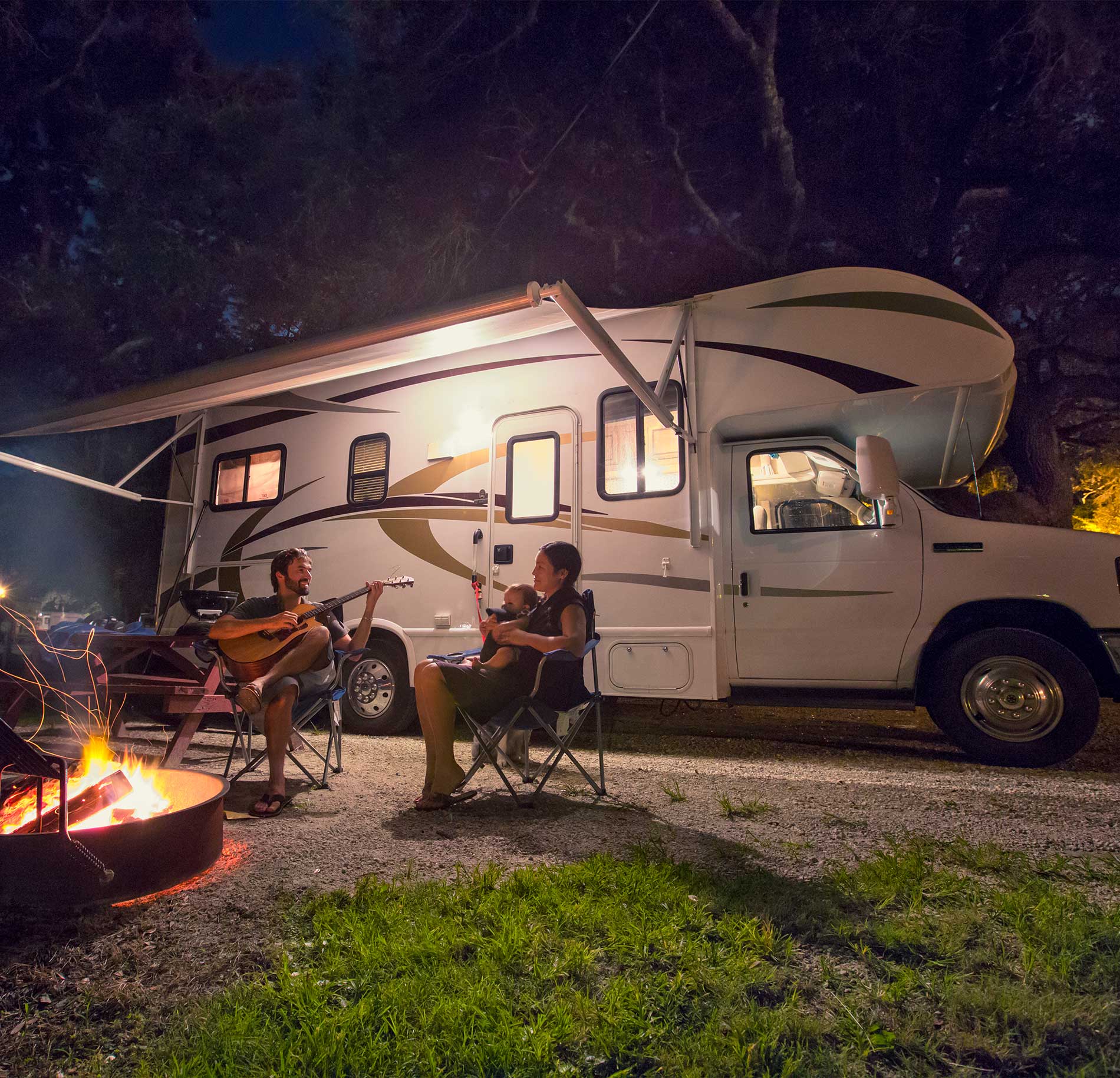 A family sitting around a campfire in front of an RV