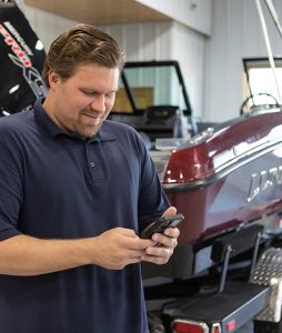 A man smiling at his phone in front of a boat