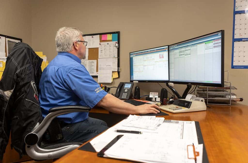 A man sitting at a desk in front of two computer monitors