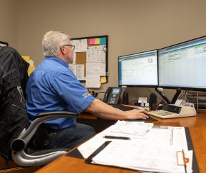 A man sitting at a desk in front of two computer monitors