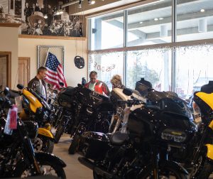 Three people inside of a motorcycle showroom looking at motorcycles
