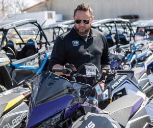 A man in a lot full of powersport vehicles looking at a motorcycle