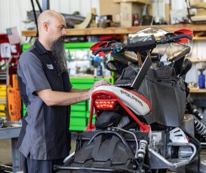 A technician looking at a motorcycle in a shop
