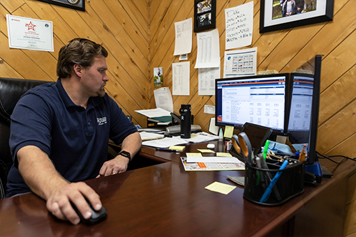 Image of a man working at a desk in front of two computer monitors.