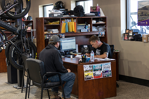 Image of a man behind a desk looking at a piece of paper helping a customer.