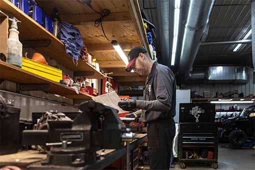 Image of a technician looking at a document at shop table.