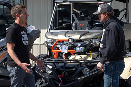 Image of two men talking in front of a powersports vehicle.
