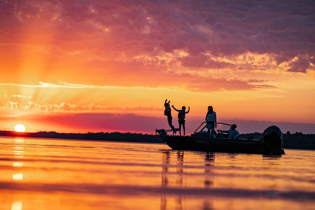 Family enjoying the lake on a boat at sunset.