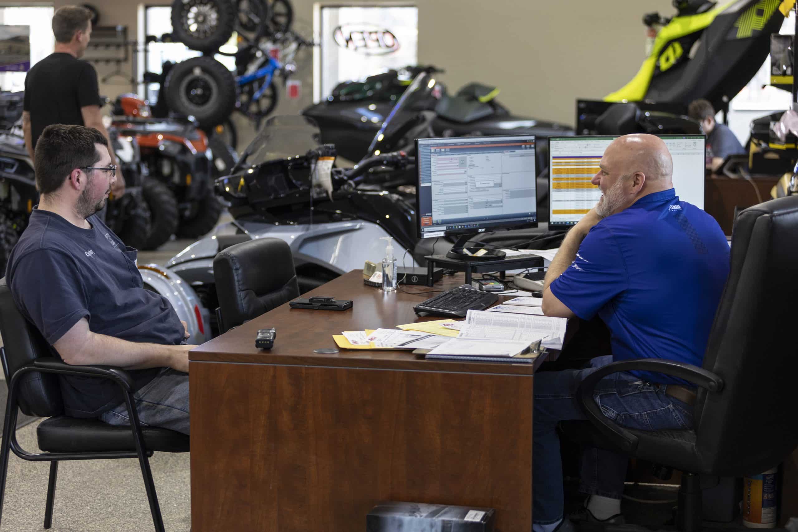Two guys talking at a desk